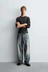 Pantalón de jean azul con efecto lavado y estampado, corte holgado y amplio en toda la pierna, tiro medio, cinco bolsillos y cierre frontal con cremallera y botón.