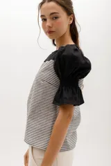 Blusa de rayas horizontales grises y blancas, con mangas abullonadas cortas negras y escote redondo.