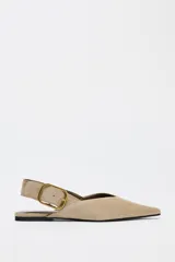 Zapato plano destalonado color beige, de serraje, con punta fina y tira trasera con hebilla metálica.