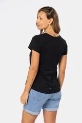 Remera color beige de corte clásico, con cuello redondo y mangas cortas. Presenta una botonadura frontal parcial con botones personalizados.