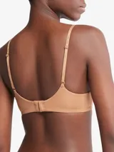 Corpiño color piel de Calvin Klein, con breteles finos ajustables con logo de la marca, escote en V y copas con relleno ligero sin aro.