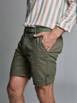 Bermuda color beige con cinturón, corte regular fit, dos bolsillos delanteros, dos traseros, un bolsillo relojero y botamanga con presilla. Aplique de badana.