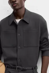 Sobrecamisa verde oscuro de corte cuadrado, con cuello solapa, manga larga con puños abotonados, bolsillos de parche en el pecho y bolsillos laterales en la cadera. Cierre frontal con botones.