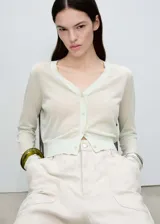 Cardigan color verde agua, de tejido de punto fino, corte crop, cuello de pico y cierre frontal con botones.