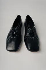 Ballerinas negras de cuero con punta redondeada y detalle de lazo ajustable.