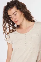 Remera color beige con cuello redondo, mangas cortas, bolsillo pequeño en el pecho y media botonadura frontal.