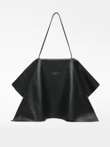 Bolso negro de piel bovina con doble capa con caída y godets laterales. Tiene asa corta de hombro y logo grabado.