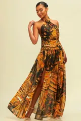 Vestido largo con estampado de hojas en tonos naranja y negro, con cuello halter y abertura en la pierna.