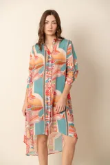 Camisa larga con estampado abstracto en tonos celeste, naranja y gris. Tiene cuello camisero, cierre frontal con botones y mangas largas.