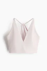 Top deportivo color rosa claro, de sujeción suave, confeccionado en tejido funcional con tecnología SoftMove™ y DryMove™. Tiene breteles finos cruzados en la espalda y copas forradas con relleno extraíble.