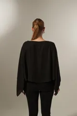 Blusa negra holgada de poliéster con mangas largas y cuello redondo.