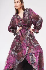 Vestido largo con estampado floral en tonos fucsia, rojo, blanco y negro. Diseño cruzado con volantes en el escote y mangas largas abullonadas.