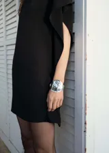 Vestido corto negro con mangas asimétricas y cuello alto.