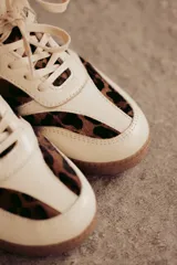 Zapatillas Adidas Samba con estampado animal print en blanco y negro, detalles en cuero beige y suela de goma color caramelo.