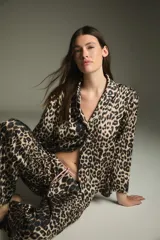Pijama de dos piezas con estampado animal print de leopardo, compuesto por una camisa de manga larga con cuello clásico y un pantalón largo con cintura elástica.