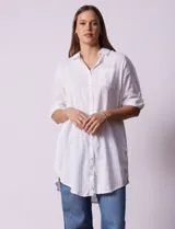 Camisola larga de algodón color blanco, marca Dash. Tiene cuello con solapa, abertura central con botones, bolsillo aplicado en el pecho, mangas regulables con presilla y botón, y bolsillos laterales en la costura.