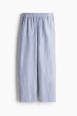 Pantalón tobillero de corte holgado en tejido liviano de mezcla de lino a rayas verticales azules y blancas. Modelo de tiro alto con elástico revestido y cordón para ajustar fino en la cintura, bolsillos al bies y piernas ajustadas.