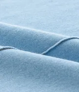 Mono peto de jeans celeste confeccionado en algodón certificado BCI. Tiene breteles anchos ajustables, bolsillos delanteros y traseros, y bajo largo.