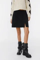 Minifalda marrón de cuero descarne, corte recto con abertura frontal.