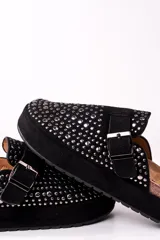 Zueco negro con plataforma, tachas plateadas y hebilla ajustable.