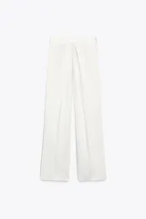 Pantalón blanco de tela satinada, tiro alto, corte ancho y pliegues en la parte delantera y trasera.