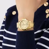 Reloj analógico Guess modelo Mist, con caja y pulsera de eslabones de acero inoxidable en tono dorado. La esfera dorada presenta índices aplicados en forma de gota y pequeños cristales incrustados en el bisel.