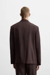 Blazer color borgoña de corte regular, con cuello de solapas de muesca, manga larga con puños abotonados, bolsillos de doble vivo en la cadera, bolsillo interior, abertura en el centro de la espalda y cierre frontal con botonadura.