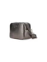 Cartera bandolera de cuero sintético color blanco con logo dorado en el frente. Tiene correa ancha de tela estampada con motivos geométricos y herrajes dorados. Incluye un dije de flecos de cuero en el lateral.