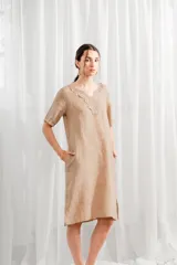 Vestido color beige de lino, de corte recto, con mangas cortas y escote en V con detalle de encaje.