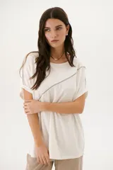 Remera negra de corte holgado con cuello redondo y mangas cortas con dobladillo. Presenta una línea diagonal blanca que cruza el frente desde el hombro hasta la cadera.