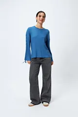 Sweater negro de punto canalé con detalle de trenzado en las mangas y lazo ajustable en el ruedo.