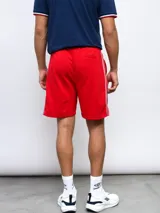 Bermuda deportiva azul marino con cordón ajustable en la cintura y bolsillos laterales. Presenta el escudo del Club Nacional de Football bordado en la pierna izquierda y un logo de Umbro en la pierna derecha. Tiene una franja blanca y roja en los laterales.