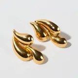 Aros colgantes dorados con forma de hojas estilizadas.