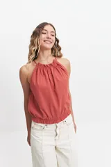 Blusa sin mangas color ladrillo, con cuello halter y elástico en el cuello y la cintura.