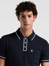 Polo de piqué azul marino de manga corta con vivos blancos en cuello y mangas, tapeta con botones y bolsillo en el pecho con logo bordado.