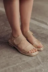 Sandalias bajas doradas de cuero, con punta cuadrada, tiras anchas y cierre con hebilla ajustable.