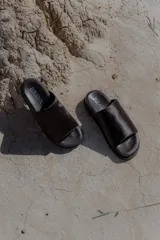 Sandalias bajas negras con capellada de cuero, forro de cuero y suela de caucho expandido.