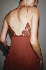 Vestido midi color ladrillo con tirantes finos, escote en pico y detalle de encaje en el busto. Tejido plisado y bajo asimétrico.