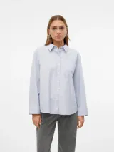 Camisa celeste de corte oversize, con cuello clásico, cierre frontal con botones, bolsillo en el pecho y mangas largas con puños abotonados.