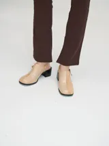 Mocasines color beige con taco bloque de madera color negro y correa trasera ajustable.