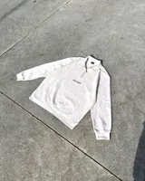 Conjunto deportivo color beige compuesto por un buzo con cierre de cremallera en el cuello y un pantalón de jogging con cintura elástica ajustable con cordón. Ambos con logo bordado en negro.