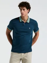 Chomba azul petróleo de manga corta con cuello polo y puños acanalados a rayas en celeste, naranja y blanco. Logo bordado en el pecho. Cierre con dos botones.