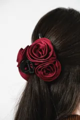 Broche para el pelo tipo pinza, color negro, con aplique de tres rosas de tela color burdeos.