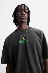 Camiseta gris oscuro con efecto lavado, cuello redondo, manga corta y estampado de textos combinados en verde neón en el delantero y la espalda.
