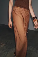 Falda midi color marrón confeccionada en lino 100%. Tiene tiro medio, cintura elástica ajustable con cordones y bajo evasé.