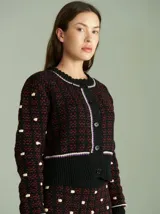 Cardigan de punto color borgoña con diseño geométrico en blanco y detalles en azul. Tiene cuello redondo, cierre frontal con botones rojos y mangas largas con puños acanalados.