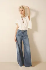 Jean corte oxford amplio de tiro medio, con cintura y cadera ajustada y piernas que se ensanchan desde la cadera hacia los tobillos con recortes en los laterales que le da un vuelo mayor a la pierna. Tejido rígido azul con lavado stone, localizado y bigotes. Con cierre y botón.