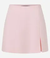 Short pollera de sastrería color rosa pálido, con cintura fija, corte corto, detalle de encaje en el frente y cierre lateral oculto.