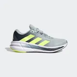 Championes de running Adidas Questar 3, color gris claro con tres franjas laterales en amarillo neón. Presentan detalles en azul oscuro en el talón y la suela, con entresuela blanca y tecnología Cloudfoam Plus.