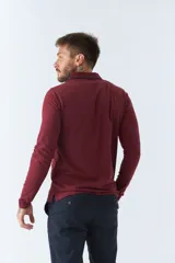 Polo de manga larga negra con cuello clásico, tapeta de dos botones y bolsillo de parche en el pecho con ribete blanco. Logo de la marca bordado en blanco sobre el bolsillo.